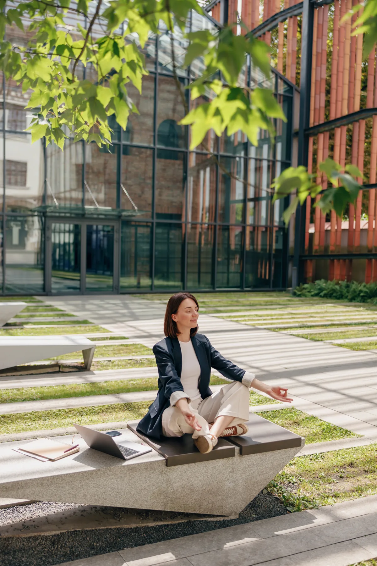 A professional woman in calm meditation in a sunlit courtyard